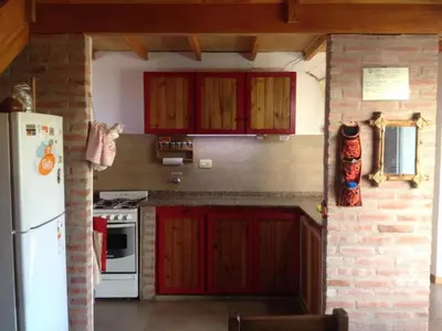 a kitchen with red cabinets and a white refrigerator at Cabaña La Lechuza en LAS RABONAS in Mina Clavero