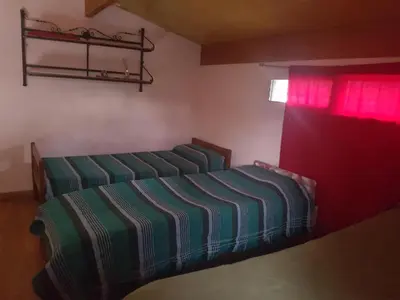 a bedroom with two beds and a window at Cabaña La Lechuza en LAS RABONAS in Mina Clavero