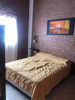 a bed in a bedroom with a brick wall at Cabañas Ipachi Naguan in Villa Rumipal