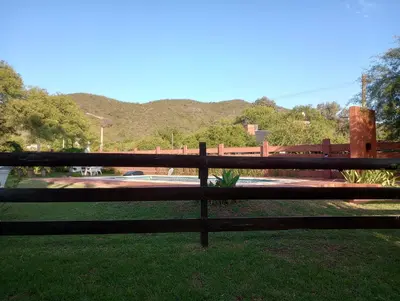 a wooden fence in a park with mountains in the background at Cabañas Ipachi Naguan in Villa Rumipal