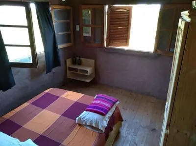 a bedroom with a bed and two windows at Cabaña El Colibri en Villa Amancay in Villa Amancay