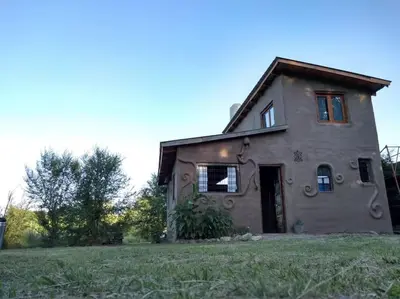 an old stone house with a grassy yard at Cabaña El Colibri en Villa Amancay in Villa Amancay