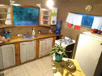 a kitchen with a sink and a refrigerator and a table at Cabaña El Colibri en Villa Amancay in Villa Amancay