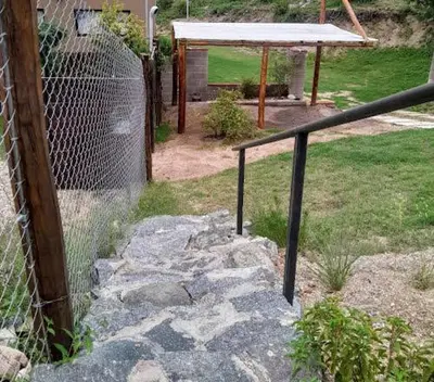 a fence and some rocks and a gate and a staircase at Piedramadre hermosa cabaña a metros del río hasta 4 huéspedes in Cordoba