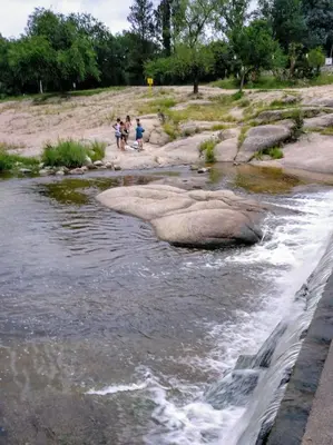 a group of people standing on the rocks in a river at Piedramadre hermosa cabaña a metros del río hasta 4 huéspedes in Cordoba