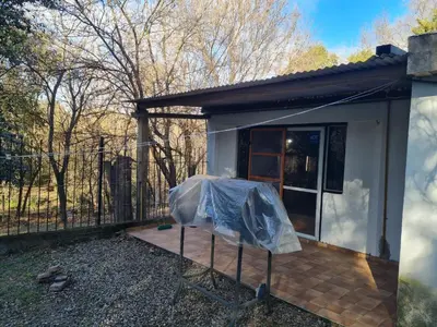 a small white house with a porch and a fence at Cabañas los Nonitos in Villa Los Aromos