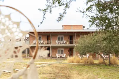a brick house with white chairs on the porch at Apart de Sierras in Nono