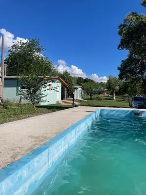 a swimming pool with blue water in front of a house at Cabañas D Noris in Los Hornillos