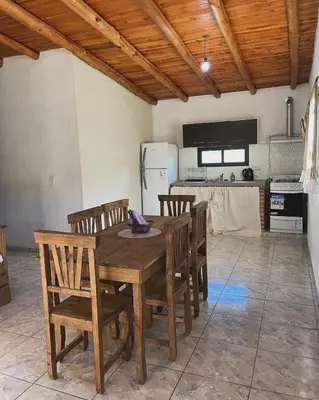 a kitchen with a wooden table and chairs at Cabañas D Noris in Los Hornillos
