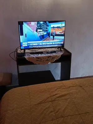 a computer monitor sitting on a desk next to a bed at departamento en zona residencial in Cordoba