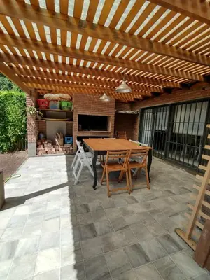 a wooden pergola on a patio with a wooden table at Casa Privada Carlos Paz con piscina a dos cuadras del rio in Villa Carlos Paz