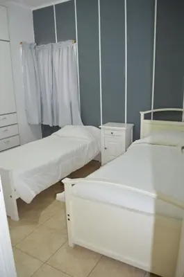 two beds in a room with white furniture at Complejo Fatima in Villa Dolores