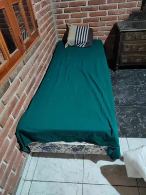 a bed with a green sheet on a brick wall at Amables 2 in Salsacate