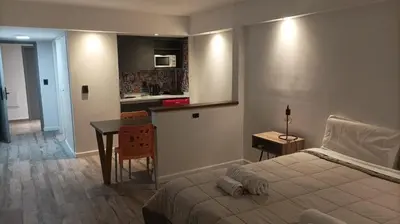 a bedroom with a bed and a table and a kitchen at Departamento 611 - Edificio VILAUT by INMOVE Temporarios in Cordoba
