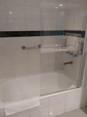 a shower with a glass door next to a tub at Departamento 611 - Edificio VILAUT by INMOVE Temporarios in Cordoba