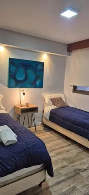a bedroom with two beds and a table and a painting at Departamento 216 - Edificio VILAUT by INMOVE Temporarios in Cordoba