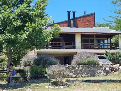 a woman sitting on a bench in front of a house at Complejo Terrazas al Champaqui in Villa Yacanto