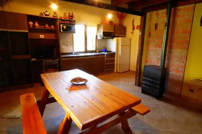 a kitchen with a wooden table and a kitchen with a refrigerator at Complejo Terrazas al Champaqui in Villa Yacanto
