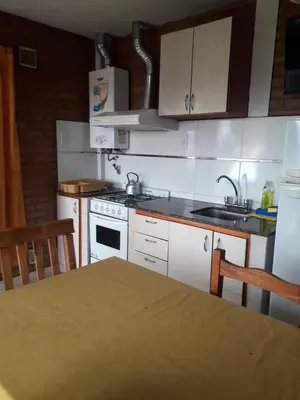 a kitchen with white cabinets and a table and a sink at Altos del Plata in Villa Carlos Paz