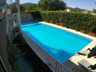 a large blue swimming pool next to a building at Altos del Plata in Villa Carlos Paz