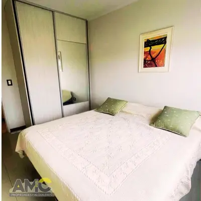 a bedroom with a large white bed with green pillows at Departamento céntrico de 2 habitaciones y Pileta Edificio Sommet in Villa Carlos Paz