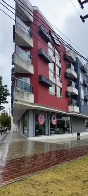 a red building with signs in front of it at Departamento céntrico de 2 habitaciones y Pileta Edificio Sommet in Villa Carlos Paz