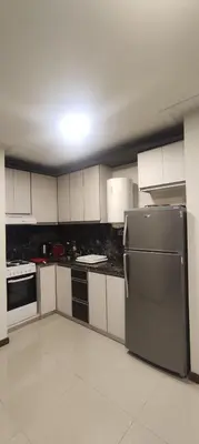 a kitchen with white cabinets and a stainless steel refrigerator at Departamento céntrico de 2 habitaciones y Pileta Edificio Sommet in Villa Carlos Paz