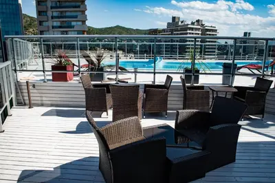 a deck with chairs and tables and a swimming pool at Departamento céntrico de 2 habitaciones y Pileta Edificio Sommet in Villa Carlos Paz