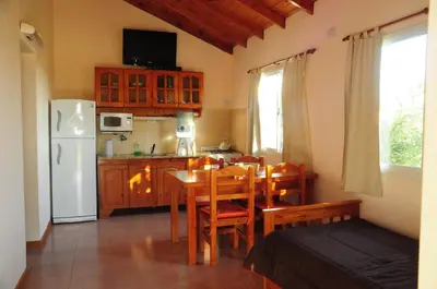a kitchen and dining room with a table and a refrigerator at Corazon de Montaña in Merlo