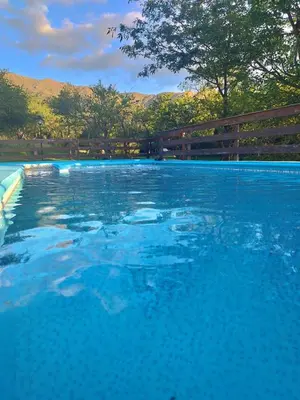 a swimming pool with blue water in front of a fence at Corazon de Montaña in Merlo