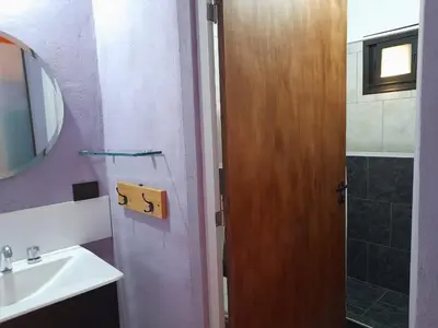 a bathroom with a sink and a wooden door at Cabañas R&E in Mina Clavero