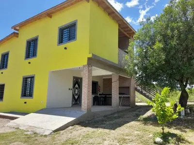 a yellow and white house with a tree at Cabañas R&E in Mina Clavero