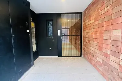 a hallway with a black door and a brick wall at Apto amoblado temporario in Cordoba