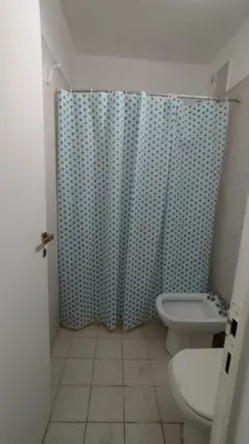a bathroom with a toilet and a shower curtain at El refugio - Cuatro Horizontes in Villa General Belgrano