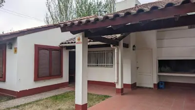 a white house with a red door and a porch at El refugio - Cuatro Horizontes in Villa General Belgrano