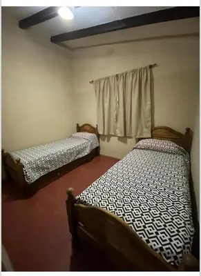 two beds sitting in a room with a window at La casita in Villa Carlos Paz