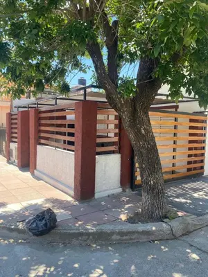 a tree sitting next to a building with a fence at La casita in Villa Carlos Paz
