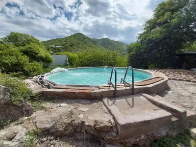 a large swimming pool in a yard with mountains at Pintacho Cabañas, casa in Villa Anizacate