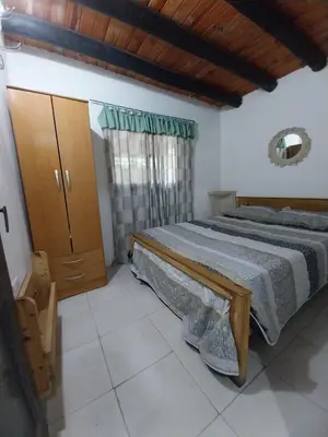 a bedroom with a large bed and a wooden cabinet at Pintacho Cabañas, casa in Villa Anizacate