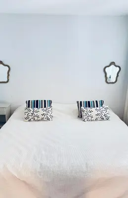 a white bed with two pillows on top of it at Casa Milos para dos personas frente al rio in Santa Rosa de Calamuchita