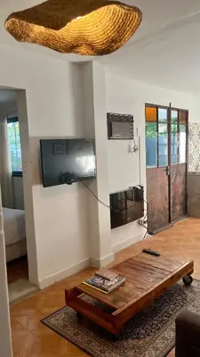 a living room with a table and a flat screen tv at Casa Milos para dos personas frente al rio in Santa Rosa de Calamuchita