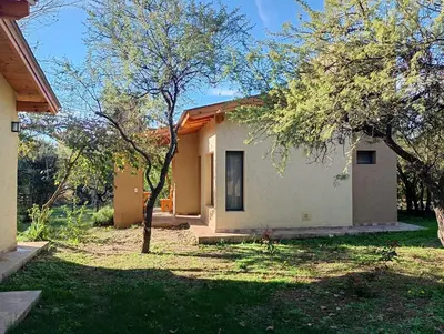 a small white house with trees in the yard at Las Moras in Santa Rosa de Calamuchita