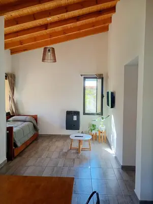 a living room with a bed and a table at Las Moras in Santa Rosa de Calamuchita