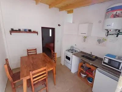 a small kitchen with a wooden table and a sink at Los Luises - Departamentos Céntricos in Mina Clavero