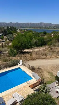 a swimming pool with chairs and a view of the water at Complejo Refugio Playa Perelli in Villa Carlos Paz