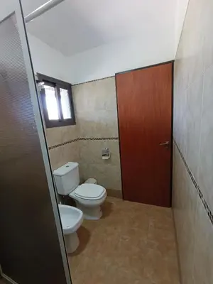 a bathroom with a toilet and a window and a door at Complejo Refugio Playa Perelli in Villa Carlos Paz