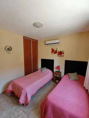 two beds in a room with pink sheets at Complejo Refugio Playa Perelli in Villa Carlos Paz