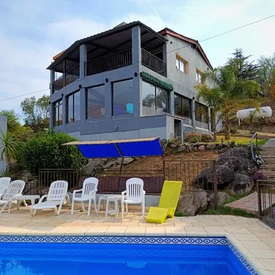 a house with a swimming pool in front of a house at Complejo Refugio Playa Perelli in Villa Carlos Paz