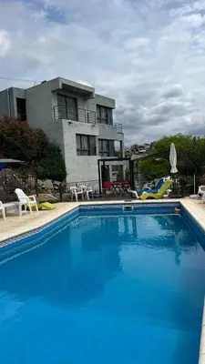 a large blue swimming pool in front of a building at Complejo Refugio Playa Perelli in Villa Carlos Paz
