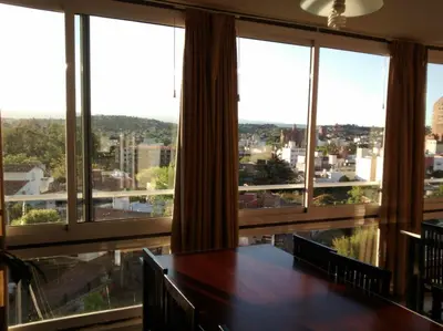 a large room with a table and large windows at Departamento, Terraza con PISCINA, SUM y PARRILLAS a 2 cuadras de PEATONAL in Villa Carlos Paz